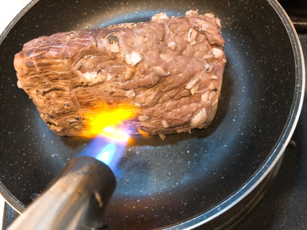 高温にしたフライパンでローストビーフの表面を焼く。またはガスバーナーで表面を炙る
